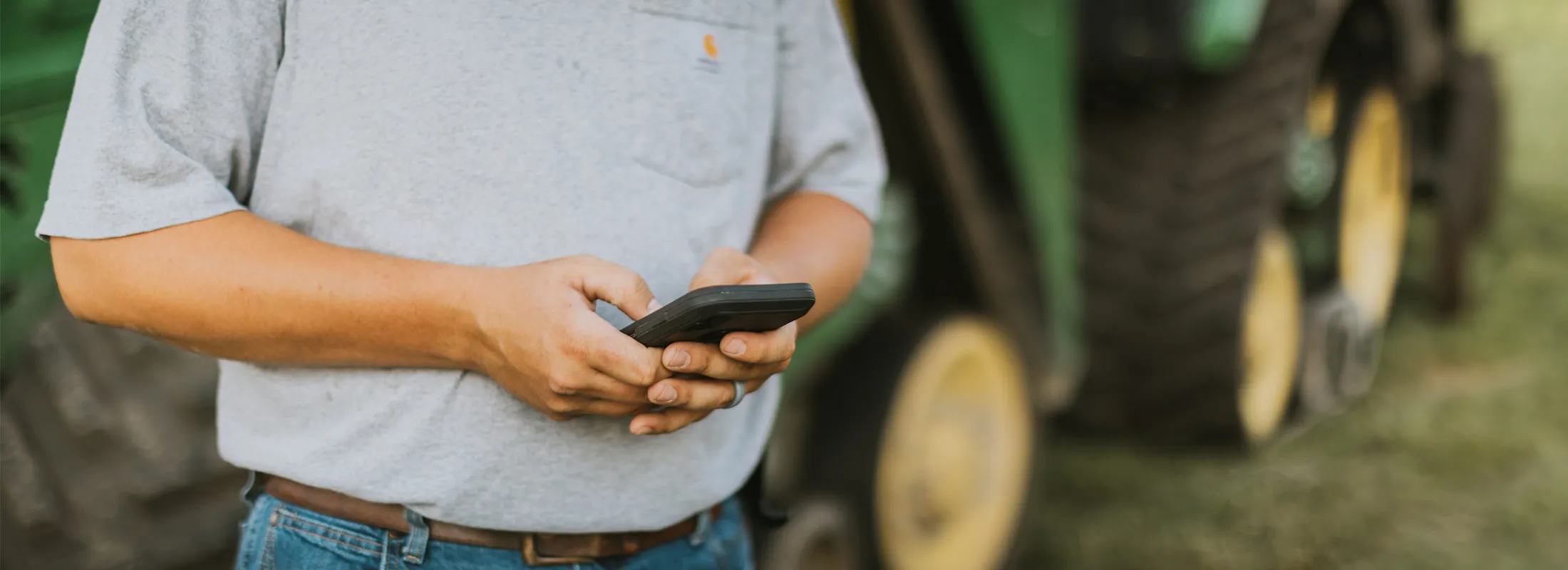 a person on their phone with a tractor behind them