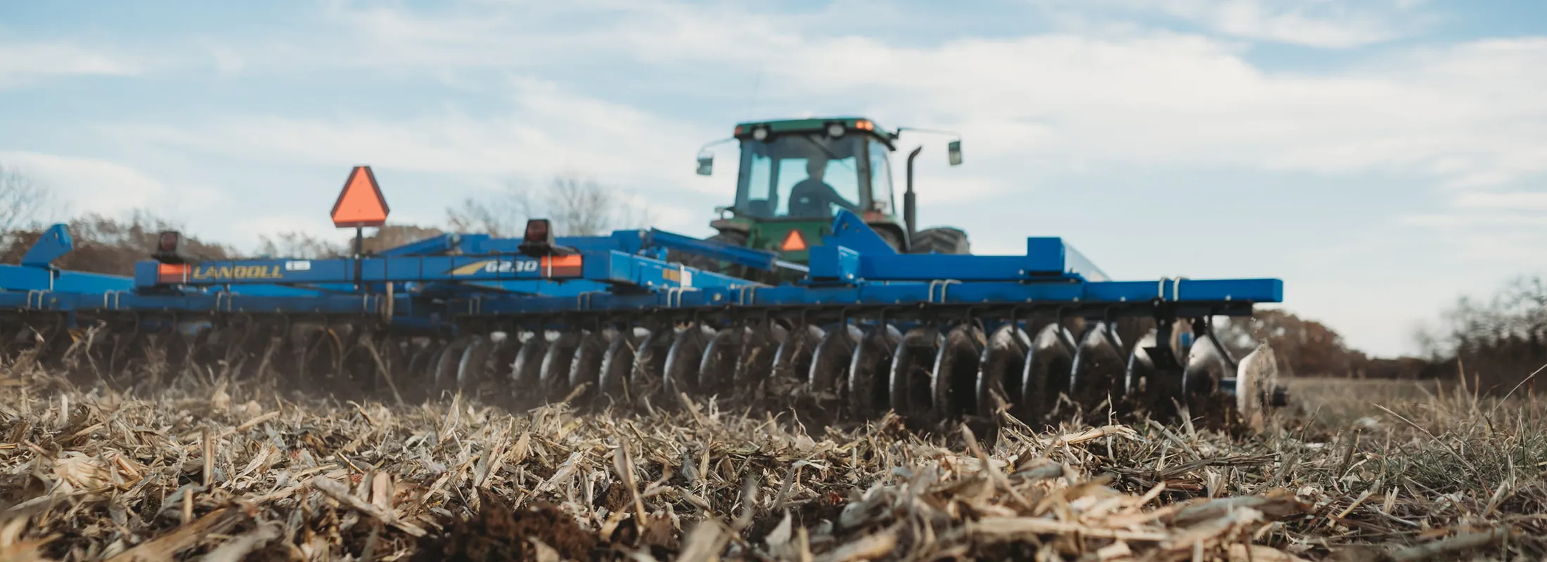 a disc harrow being pulled by a tractor across a field