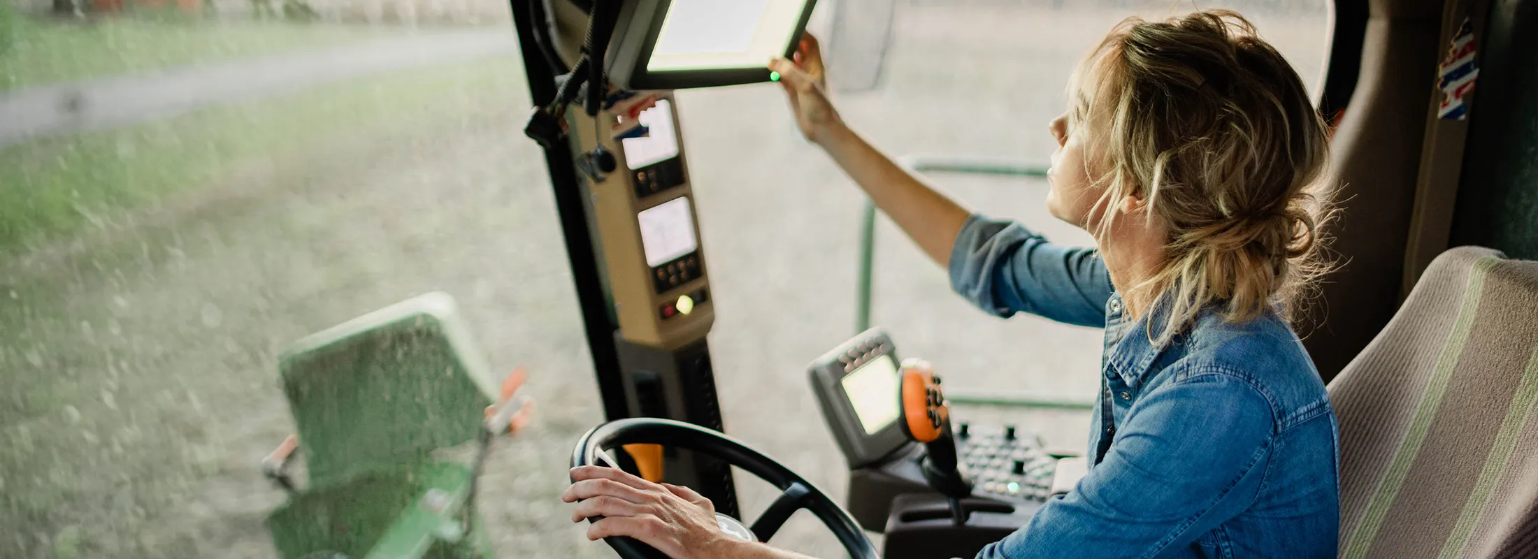 a woman inside of a tractor adjusting the control screen
