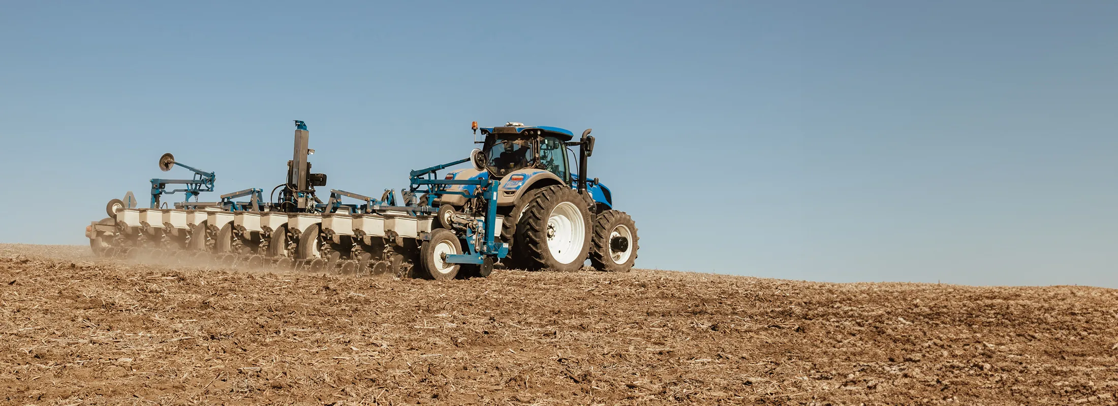 a tractor pulling a row crop planter across a field