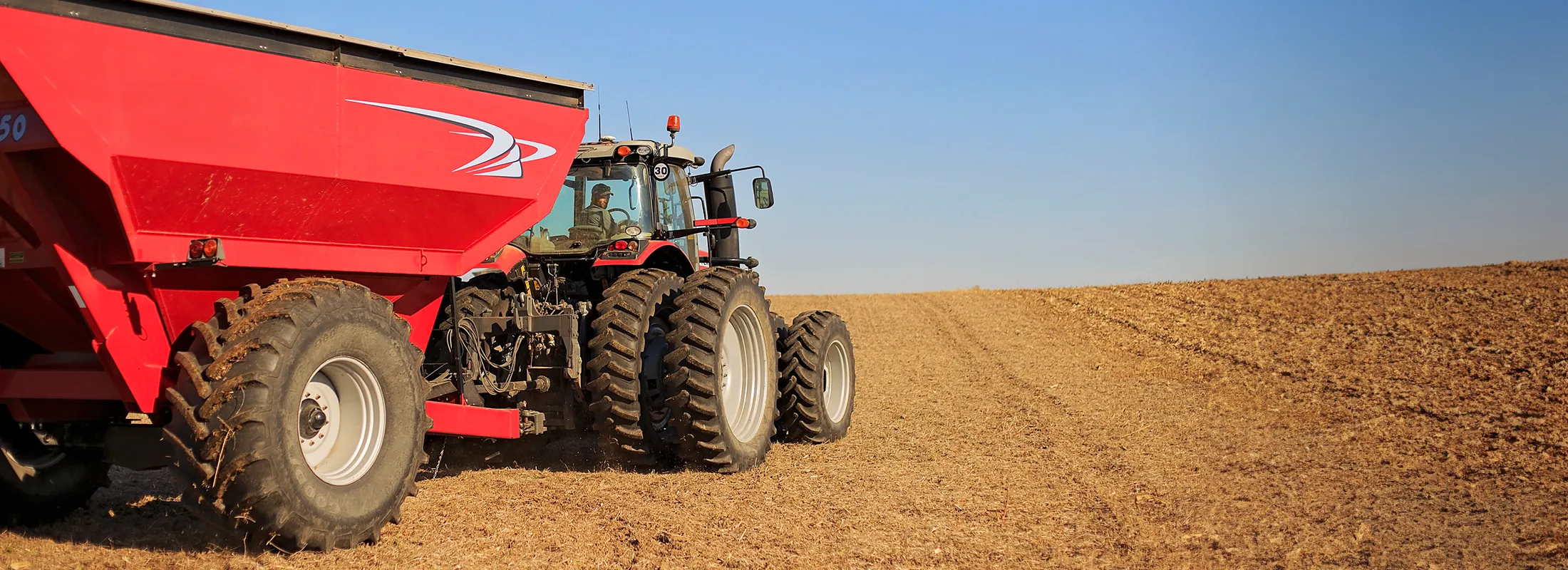 a tractor pulling an agricultural trailer across a field