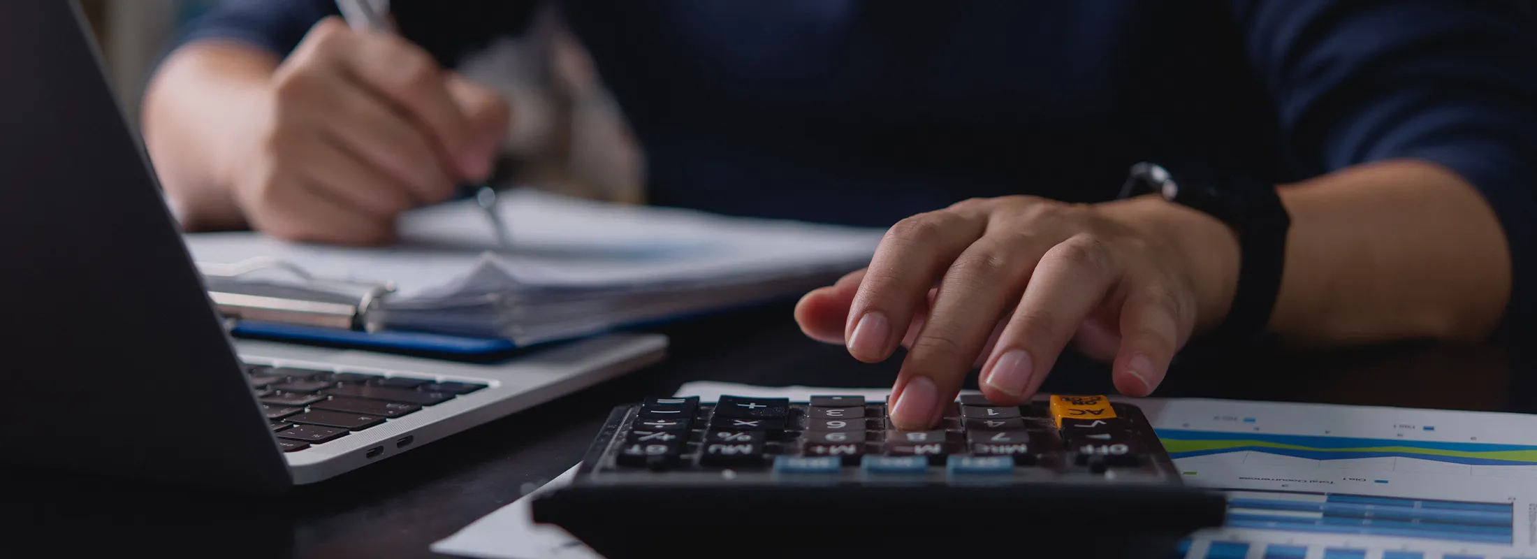 a person writing something down while using a calculator